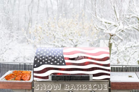 Grilling meat on a barbecue in the snow. Grill cover with the Stars and Stripes lactated.
