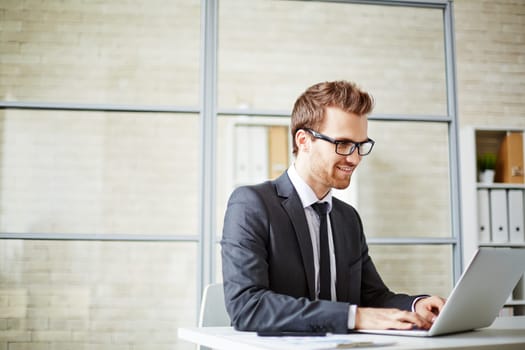Happy young businessman in formalwear networking in office