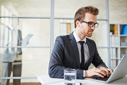 Young businessman in formalwear typing on laptop