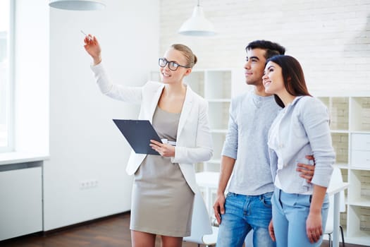 Pretty realtor consulting young couple about buying flat