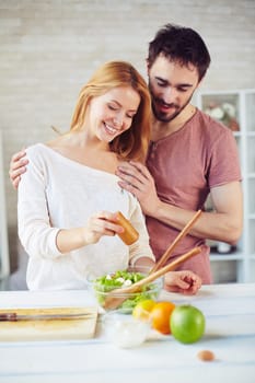 Happy young couple cooking vegetarian salad in the kitchen