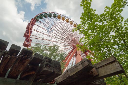 Abandoned Ferris wheel with wooden beams in the foreground