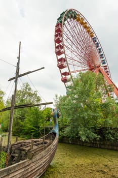 Abandoned Ferris wheel and Viking ship in the amusement park