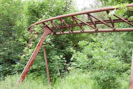 Roller coaster track on high stands leads into the bushes