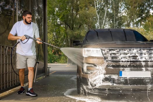 man washing a car in a self-service car wash station with wahing foam. Wash car self-service station. High quality photo