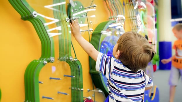 Cute little boy playing with educational mechanism in museum of science.