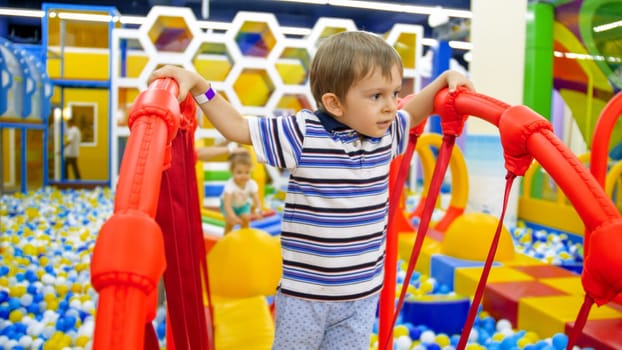 Portrait of cute little boy balancing on balancing board in children playroom at shopping mall.