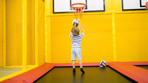 Cute little boy playing in basketball on playground at amusement park.