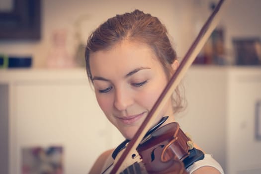 Pretty young girl practices on her violin, acoustic music