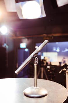 Metal microphone in the studio, studio lights in the blurry background