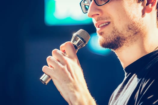 Young man on the stage is talking into a microphone, speech