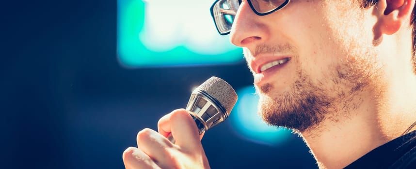 Young man on the stage is talking into a microphone, speech
