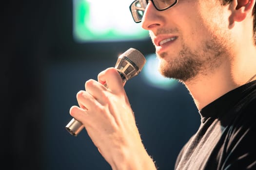 Young man on the stage is talking into a microphone, speech