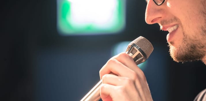 Young man on the stage is talking into a microphone, speech