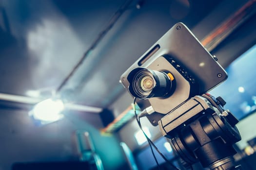 Film camera on a tripod in a television broadcasting studio, spotlights and equipment
