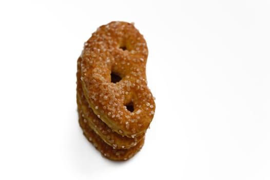 A crispy kidney bean-shaped treat glistens with salt crystals on a clean surface.