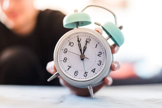 Man is holding an alarm clock, sunshine in the morning, blurry background