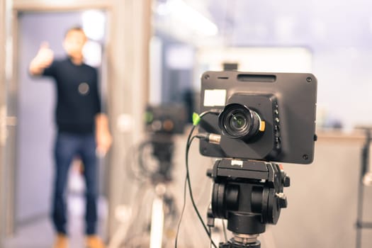 Lens of a film camera in an television broadcasting studio, spotlights and equipment, director in the background