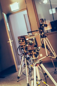 Film camera on a tripod in a television broadcasting studio, spotlights and equipment