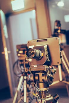 Film camera on a tripod in a television broadcasting studio, spotlights and equipment