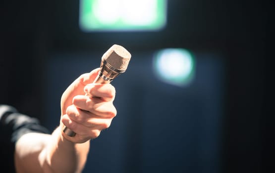 Person is holding up a metal microphone and wants to interview someone, copy space