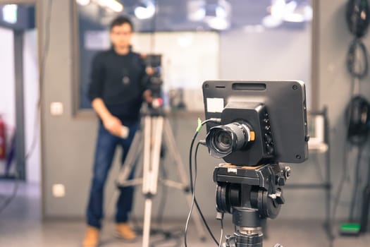 Film camera on a tripod in a television broadcasting studio, cameraman in the blurry background