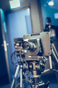 Film camera on a tripod in a television broadcasting studio, spotlights and equipment