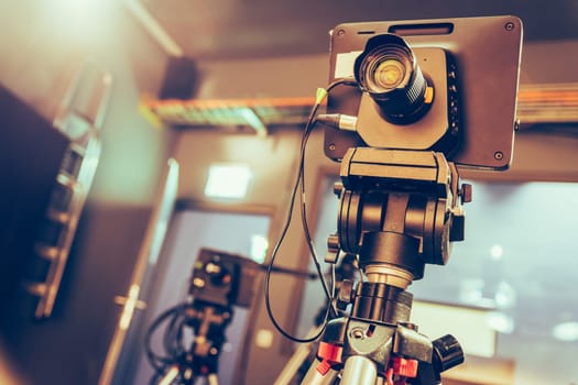 Film camera on a tripod in a television broadcasting studio, spotlights and equipment