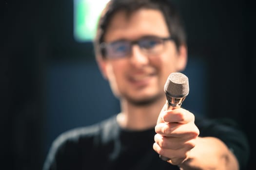Young man on the stage is talking into a microphone, speech, face is blurry