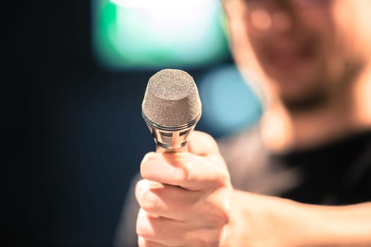 Young man on the stage is talking into a microphone, speech, face is blurry