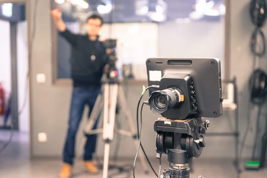 Film camera on a tripod in a television broadcasting studio, cameraman in the blurry background