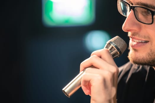 Young man on the stage is talking into a microphone, speech