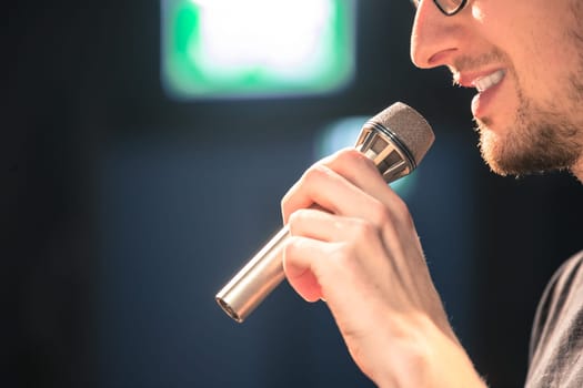 Young man on the stage is talking into a microphone, speech