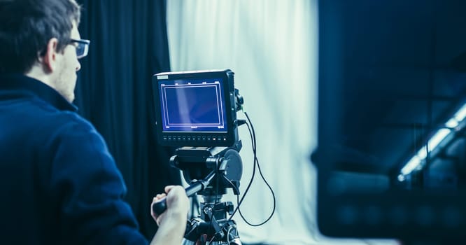 Male cameraman is operating a film camera in a television studio
