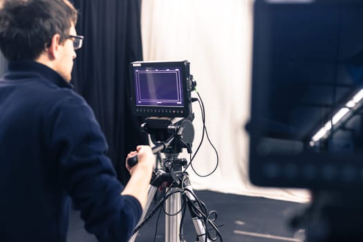 Male cameraman is operating a film camera in a television studio