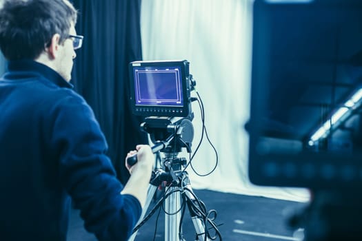 Male cameraman is operating a film camera in a television studio