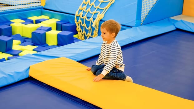Cute little boy having fun and playing on trampolines at amusement park.