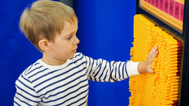 Portrait of little boy living print of his hand on educational game at amusement park.