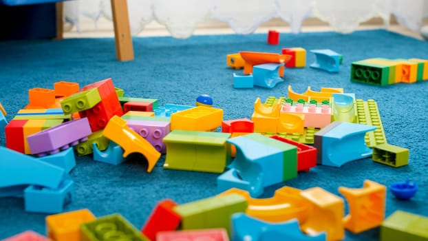 Closeup image of messy floor in playroom covered with colorful toy blocks.