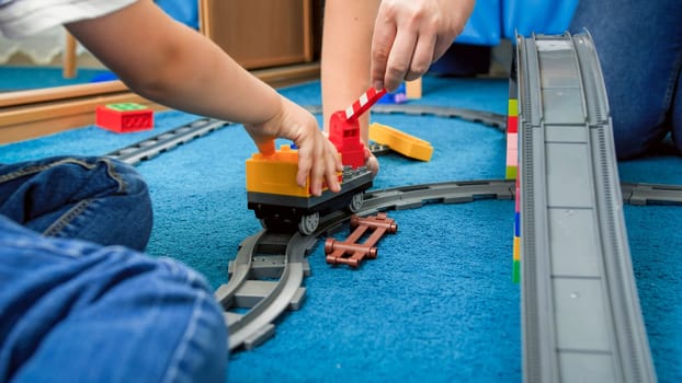 Closeup image of caring parent playing with child on floor at playroom.