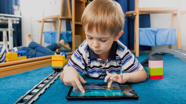 Portrait of smiling boy using pad computer for playing games.