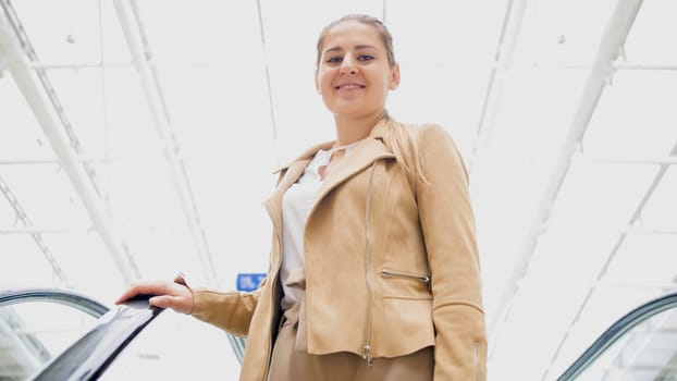 Portrait of beautiful smiling young woman on ecalator in shopping mall.