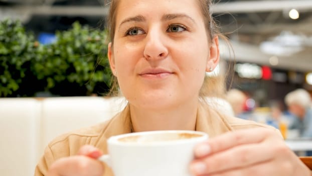 Portrait of beautiful smiling woman holding cup of coffee in cafe.