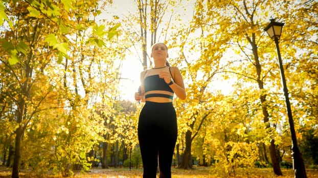 Portrait of beautiful sporty woman jogging and exercising in autumn park.