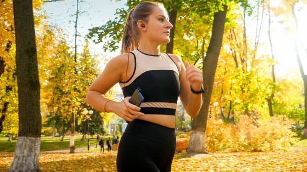 Portrait of beautiful sexy woman doing fitness and jogging at autumn park.