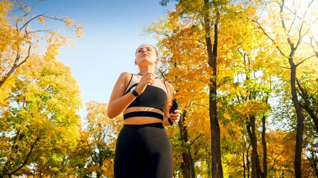 Portrait of beautiful sexy woman exercising and running in autumn park at sunrise.