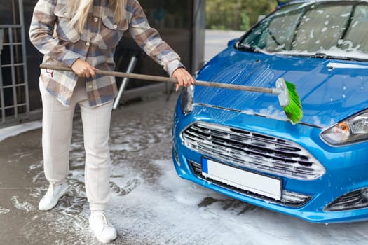 the women herself at the car wash washes the car with a brush.