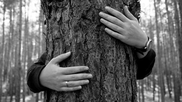 Black and white iamg eof young woman embracin gbig old tree in forest. Concept of love, ecology protection and harmony with nature.