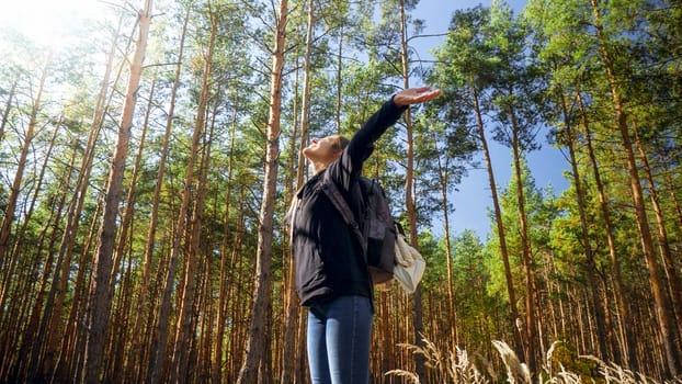 Portrait of smiling happy woman hiking in forest with outstretched hands . Concept of freedom and harmony with nature