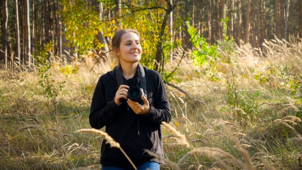 Portrait of beautiful smiling woman with digital camera working as photographer in forest.
